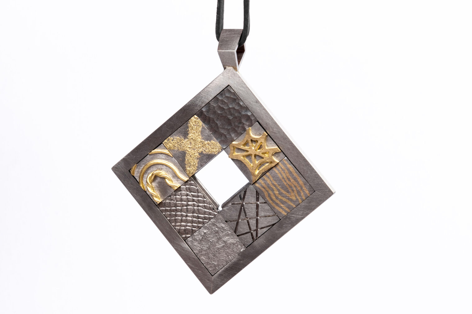 Ein Anhänger aus Weiß- und Gelbgold Gelbgold mit gegeneinander frei verschiebbaren Metallfeldern unterschiedlicher Gestaltung. 